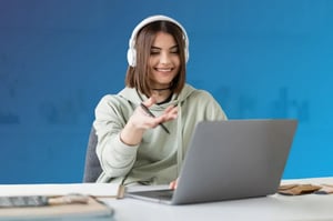 A teenage girl seated at a desk studying with an open laptop and notebook.