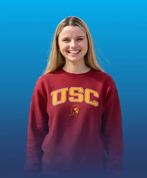 Smiling student wearing a maroon University of Southern California sweatshirt against a blue background.